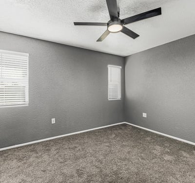 Comfortable bedroom featuring soft carpet, ceiling fan, and bright windows. This Sun City home offers updated finishes and inviting living spaces.