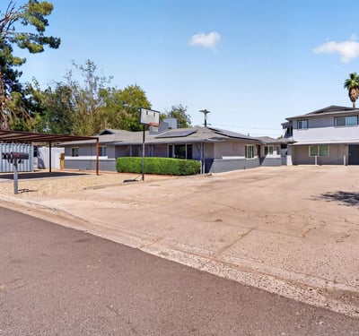 Wide-angle view showcasing the triplex layout, updated exterior, and spacious parking ideal for investors seeking Phoenix rental property.