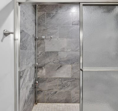 Detailed view of tiled walk-in shower with sleek finishes and glass doors, showcasing recent bathroom upgrades.