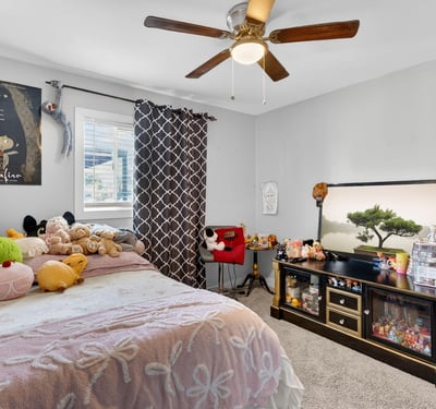 Cozy bedroom with plush carpeting, ceiling fan, and inviting layout, ideal for everyday comfort.
