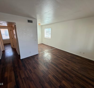 Large living room with rich wood-look flooring, neutral finishes, and a bright open feel. The spacious layout creates a welcoming environment ideal for entertaining guests or enjoying everyday comfort.
