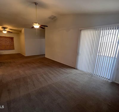 Large living room with vaulted ceilings, soft neutral finishes, and sliding glass doors that bring natural light indoors. This versatile space is ideal for entertaining guests or enjoying everyday relaxation.