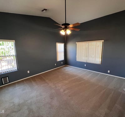 Generously sized primary bedroom with vaulted ceilings, ceiling fan, and abundant natural light. The spacious design creates a private retreat that balances comfort and functionality.