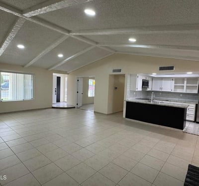 Light-filled great room seamlessly connected to the kitchen and surrounding living spaces. The vaulted ceiling design enhances openness and visual appeal throughout the home.