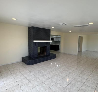 Open-concept family room showcasing a statement fireplace and seamless connection to the kitchen. The spacious design supports comfortable daily living and effortless entertaining.