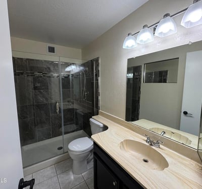 Beautifully upgraded primary bathroom highlighted by a custom tile walk-in shower with glass enclosure, modern lighting, and extended vanity space. Quality updates create a spa-inspired atmosphere.