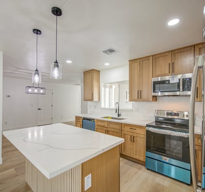 Featuring custom white oak cabinets, sleek quartz countertops, stainless steel appliances, and a generous island, this remodeled kitchen is designed for both style and convenience.