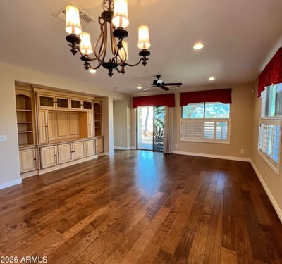 Expansive living room featuring custom built-in cabinetry, upgraded wood floors, elegant chandelier, recessed lighting, and abundant natural light. A warm and inviting gathering space designed for comfortable everyday living.