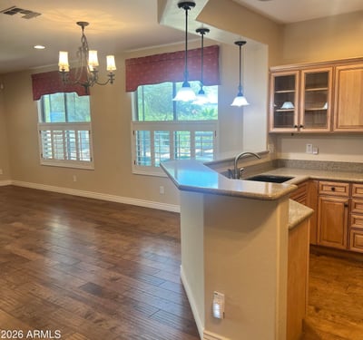 Inviting open-concept kitchen and dining area with custom cabinetry, breakfast bar, pendant lighting, plantation shutters, and upgraded flooring that creates a bright, welcoming atmosphere perfect for entertaining.