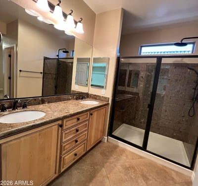 Beautiful primary bath offering dual vanities, abundant cabinetry, upgraded countertops, modern fixtures, and a spacious tiled walk-in shower. A relaxing retreat designed with both comfort and functionality in mind.