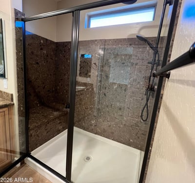 Luxurious walk-in shower with stylish tile surrounds, built-in bench seating, black framed glass enclosure, and upgraded shower fixtures creating a sophisticated spa-like experience.