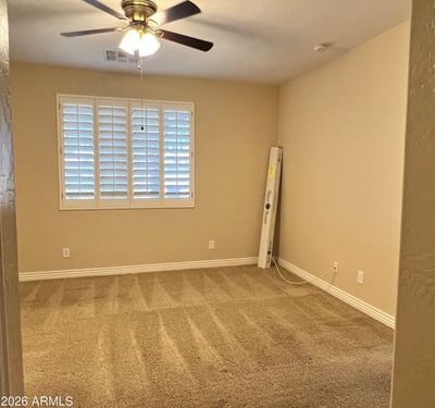 Inviting secondary bedroom featuring soft carpeting, plantation shutters, ceiling fan, and abundant natural light. Ideal as a guest suite, hobby room, or private office space.