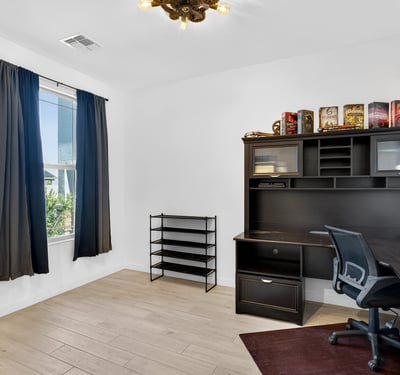 A spacious office with large windows, wood-look tile flooring, and ample room for desks or creative projects offers excellent flexibility for today's lifestyle in Surprise.