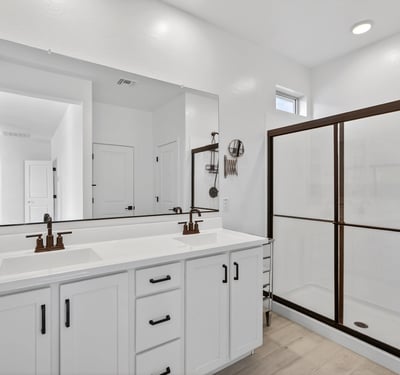 This well-appointed primary bathroom showcases dual sinks, quartz counters, modern cabinetry, black fixtures, and a spacious walk-in shower for a clean contemporary design.