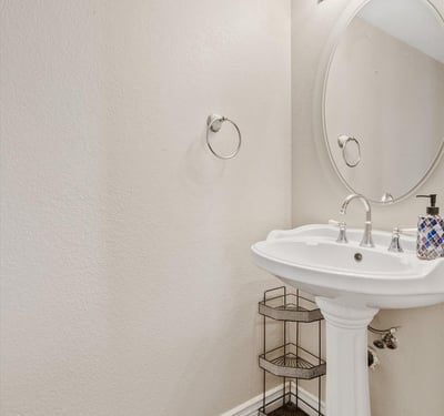 This convenient powder room features a pedestal sink, bright lighting, and neutral finishes, offering both style and functionality for guests and everyday living.