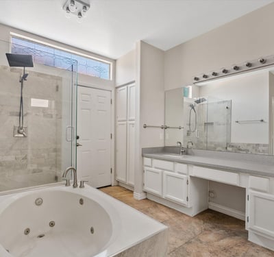 The primary bathroom offers an oversized vanity, glass walk-in shower, jetted soaking tub, and plentiful storage. Modern finishes and spacious design create a true spa-inspired retreat.