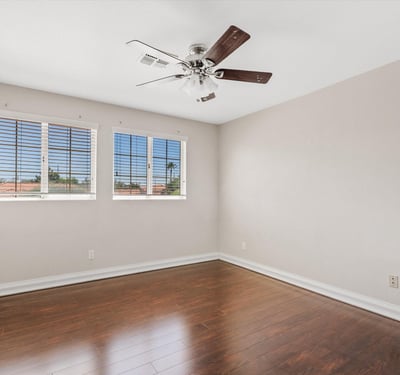 Rich wood flooring, large windows, ceiling fan, and neutral finishes make this spacious bedroom bright, comfortable, and move-in ready for family or guests.