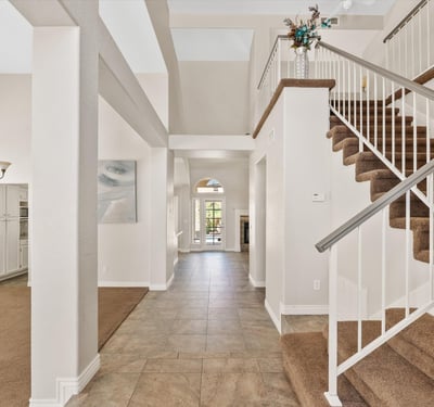 A soaring two-story entry welcomes guests with elegant tile flooring, natural light, and a sweeping staircase. The spacious foyer sets the tone for the home's open and inviting floor plan.