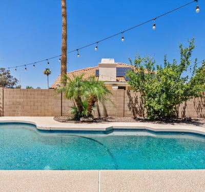 The beautifully maintained backyard features a sparkling pool, mature landscaping, decorative lighting, and privacy, creating an ideal outdoor retreat for everyday enjoyment.