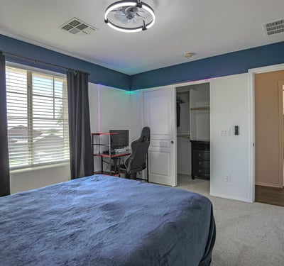 Comfortable guest bedroom with a spacious closet, soft carpeting, and large window providing excellent natural light. A functional and welcoming addition to this Waddell home.