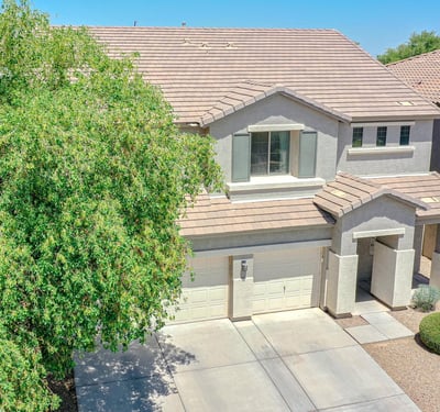 Front aerial image showcasing the home's attractive curb appeal, mature landscaping, three-car garage, and inviting exterior within a desirable Waddell neighborhood.