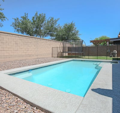 Attractive swimming pool with a baja shelf, surrounding patio, and secure fencing for added peace of mind. A standout feature that complements this beautiful Waddell home.