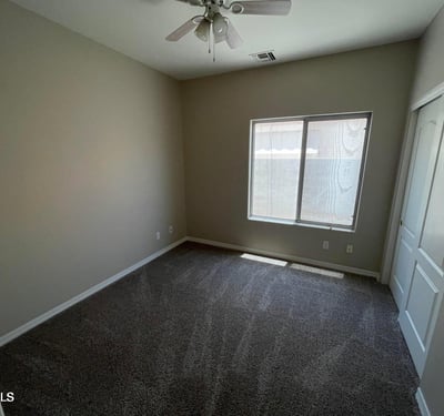 Featuring soft carpeting, a ceiling fan, natural light, and a spacious closet, this versatile bedroom easily accommodates guests, family, or a dedicated workspace.