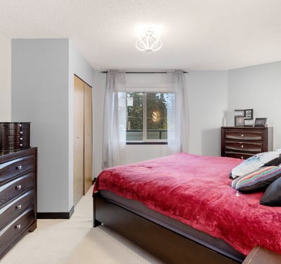 This inviting bedroom features modern decor, ample storage, and large windows for natural light.