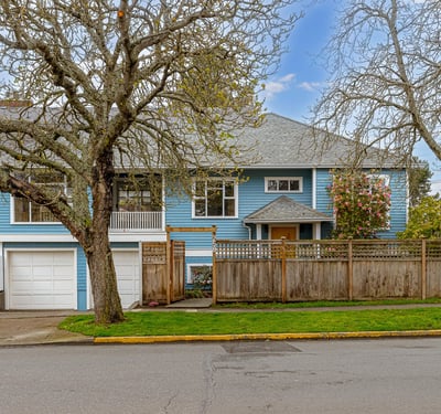 Spacious blue home with a fenced yard, featuring unique architecture and convenient garage access.
