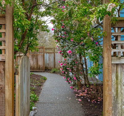 Discover a welcoming pathway adorned with vibrant blooms, leading to a private outdoor retreat.