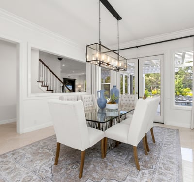 Bright dining area featuring large windows, modern lighting, and access to an outdoor patio space.