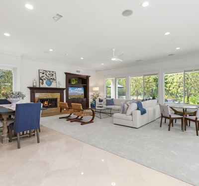 flooded with abundant natural light, showcasing a cozy fireplace and open connectivity to dining spaces.