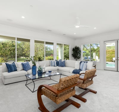 Spacious living area with large windows, offering abundant natural light and direct views of the pool.