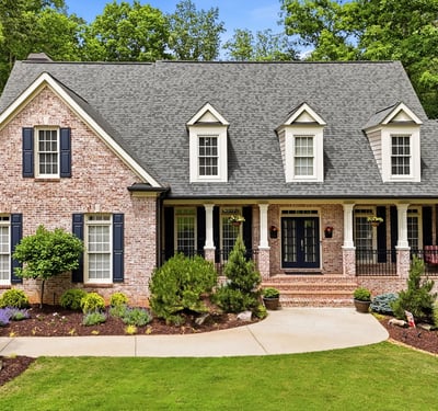 Beautifully landscaped, this spacious brick home features a welcoming porch and ample outdoor space for gatherings.