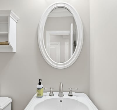 Bright, well-maintained bathroom featuring modern fixtures and a circular mirror, perfect for everyday use.