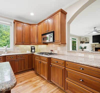 Bright kitchen featuring rich wood cabinetry, spacious countertops, and views of the landscaped outdoor area.