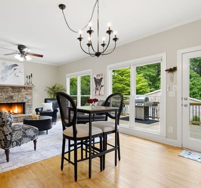 Spacious living area features a cozy fireplace and direct access to a private deck surrounded by greenery.