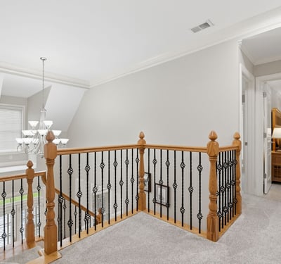 This spacious second-floor landing features a modern chandelier and leads to cozy, well-lit bedrooms.
