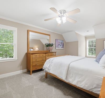 Bright and airy bedroom featuring natural light, modern ceiling fan, and ample storage in a cozy setting.