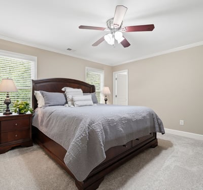 Spacious bedroom featuring natural light, a ceiling fan, and ample room for relaxation and comfort.