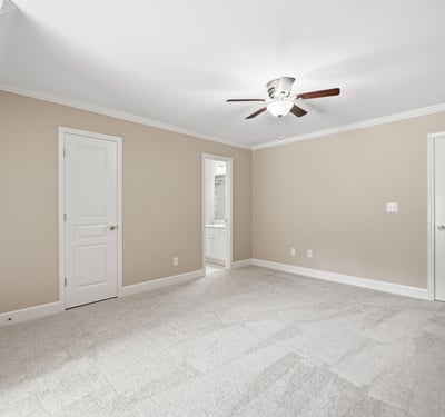 Spacious bedroom featuring soft carpeting, a ceiling fan, and access to a private bath.