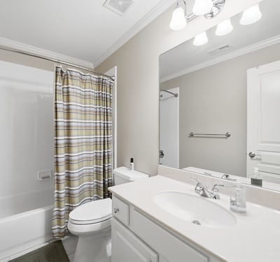 Bright and functional bathroom featuring a shower-tub combo, modern vanity, and ample storage options.