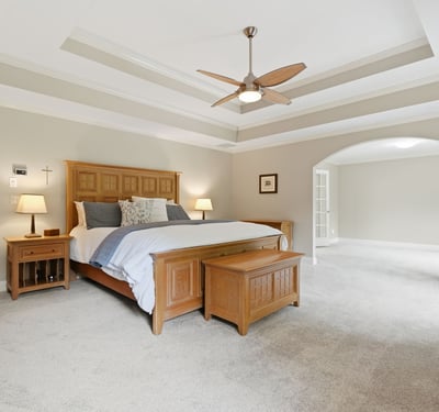 Spacious master bedroom with tray ceiling, abundant natural light, and an adjoining versatile living area.