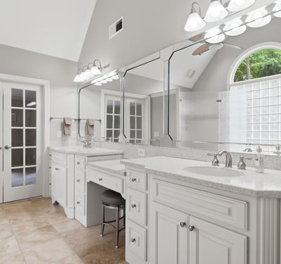 Spacious bathroom featuring dual vanities, abundant natural light, and access to a private outdoor space.