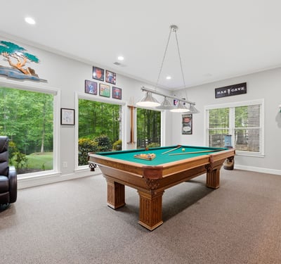 Spacious game room featuring a billiards table and large windows that invite natural light.