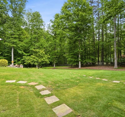 Expansive backyard featuring a winding stone pathway, surrounded by mature trees for added privacy and greenery.