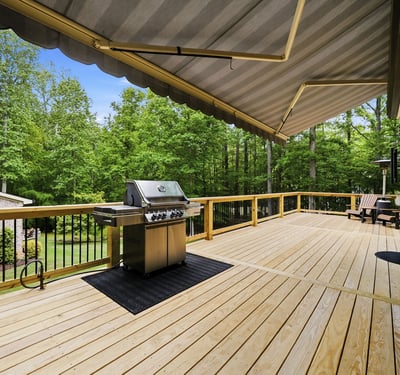 Expansive deck with built-in grill, surrounded by lush greenery, perfect for outdoor gatherings and relaxation.