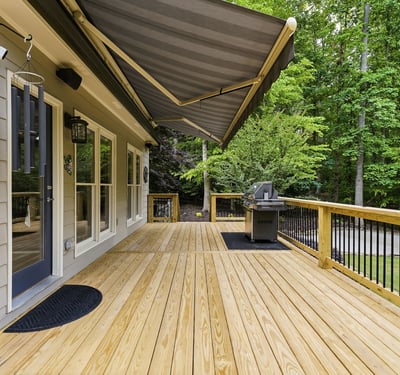 Spacious deck with awning, perfect for outdoor gatherings and overlooking lush green surroundings.