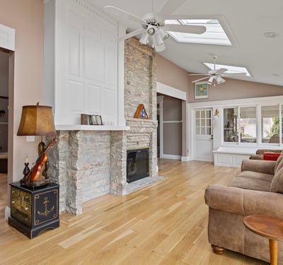 Bright and airy living space featuring a stone fireplace and large windows, perfect for entertaining or relaxing.