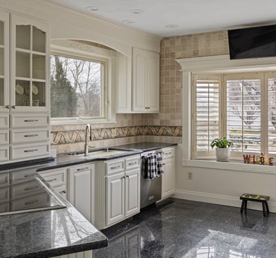 Modern kitchen featuring sleek granite countertops, abundant cabinetry, and a bright window with outdoor views.